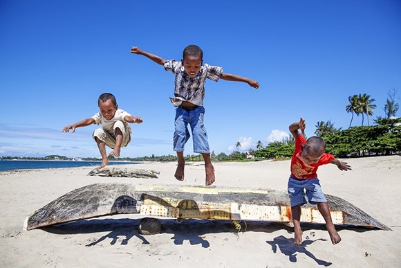 tre ragazzi saltano su una barca in una spiaggia
